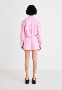 Rosa stripete skjorte- og shortsett, med krage, knappede cuffs og elastisk midje, parret med svarte hæler.