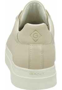 Beżowy sneaker marki GANT widziany od tyłu, z zamszowym panelem na pięcie z wytłoczonym logo oraz białą gumową podeszwą z logo GANT.