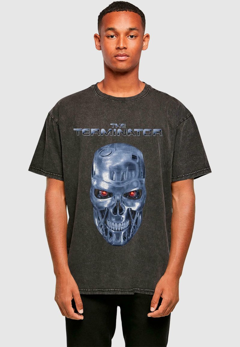Crna oversized majica od pamuka s velikim plavim i crvenim grafikonom robotske lubanje te natpisom "THE TERMINATOR" iznad.