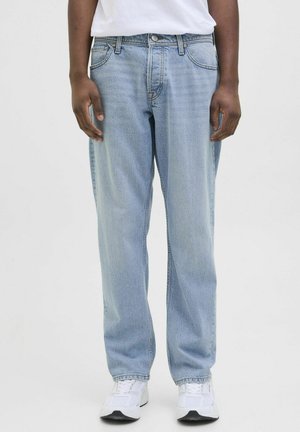 Jeans de mezclilla azul claro con corte recto, diseño de cinco bolsillos y un ligero desgaste. Llevados con una camiseta blanca sencilla y zapatillas.