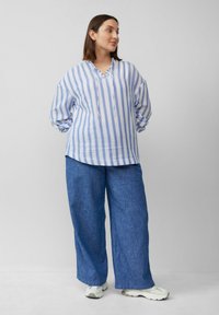 Lichte, gestreepte lange mouw shirt in blauw en wit, gecombineerd met losse blauwe linnen broek. Zachte textuur, relaxte pasvorm en casual stijl.