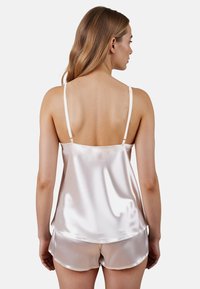 Seiden-Schlafset in Hellrosa, bestehend aus einem Top mit verstellbaren Trägern und passenden Shorts mit glattem Material und abgerundetem Saum.