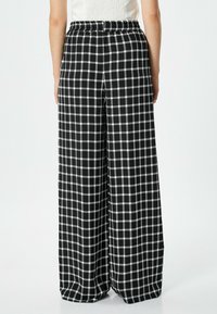 Pantalons larges à carreaux noir et blanc avec une taille élastique, présentant une coupe ample et un tissu doux pour un confort optimal.