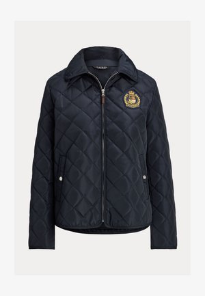 Laivastonsininen tikattu takki, jossa etuvetoketju, painonapilliset taskut, pystykaulus ja vasemmassa rinnassa kirjailtu vaakuna.