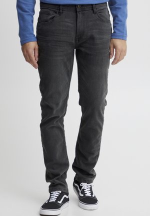 Donkergrijze denim jeans met een slim fit, vijf-pocket ontwerp, lichte vervaging en een knoopsluiting, gecombineerd met zwart-witte sneakers.
