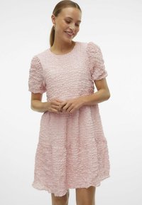 Rosa strukturerad klänning med puffärmar, volangkjol och rund halsringning. Tyget har en rynkad design för extra detaljer.
