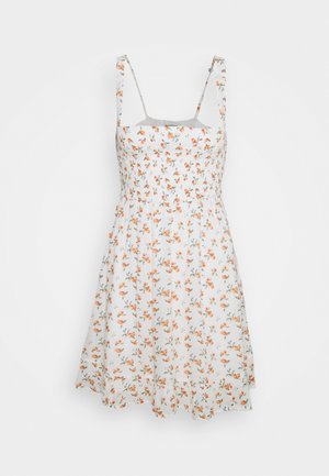 White sleeveless sundress with thin straps and small orange floral print, fitted bodice, and flared skirt.