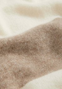 Ullblandat tyg i krämfärg och tan, som har en slät struktur med ett mjukt, lätt utseende och en subtil färggradient.