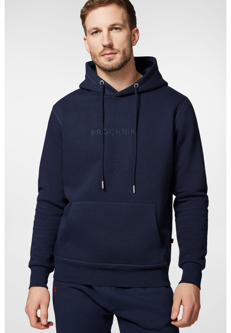 Granatowy sweatshirt z miękkiego materiału, z przednią kieszenią, sznurkiem ściągającym oraz haftowanym logo na środku. Gładka tekstura.