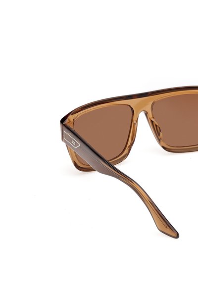 Lunettes de soleil rectangulaires translucides marron avec des verres marron assortis et un logo sur l'arête latérale, présentées sur un fond blanc.
