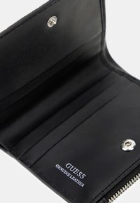 Portafoglio in vera pelle nero di Guess, aperto, che mostra gli scomparti per carte e la chiusura a bottone.