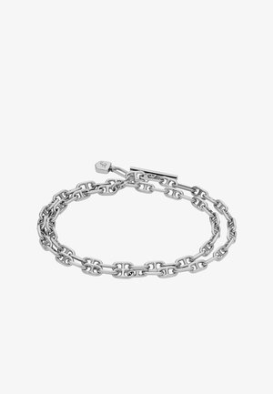 Silberne Kettenarmband mit ineinandergreifenden ovalen Gliedern, einem Toggle-Verschluss und einem kleinen Schild mit eingeprägtem Branding. Glatte, polierte Oberfläche.