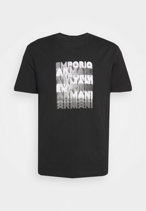 Musta lyhythihainen t-paita, jossa on keskitetty pystysuunnassa pinottu valkoinen teksti, jossa sana "ARMANI" toistuu vääristyneessä tyylissä.
