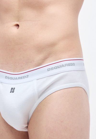 Λευκά ανδρικά εσώρουχα DSQUARED2 με ριμπ υφή, που διαθέτουν ασημί λογότυπο στη ζώνη μέσης και κόκκινη ρίγα για τόνωση. Κοντινή όψη του υφάσματος και της εφαρμογής.