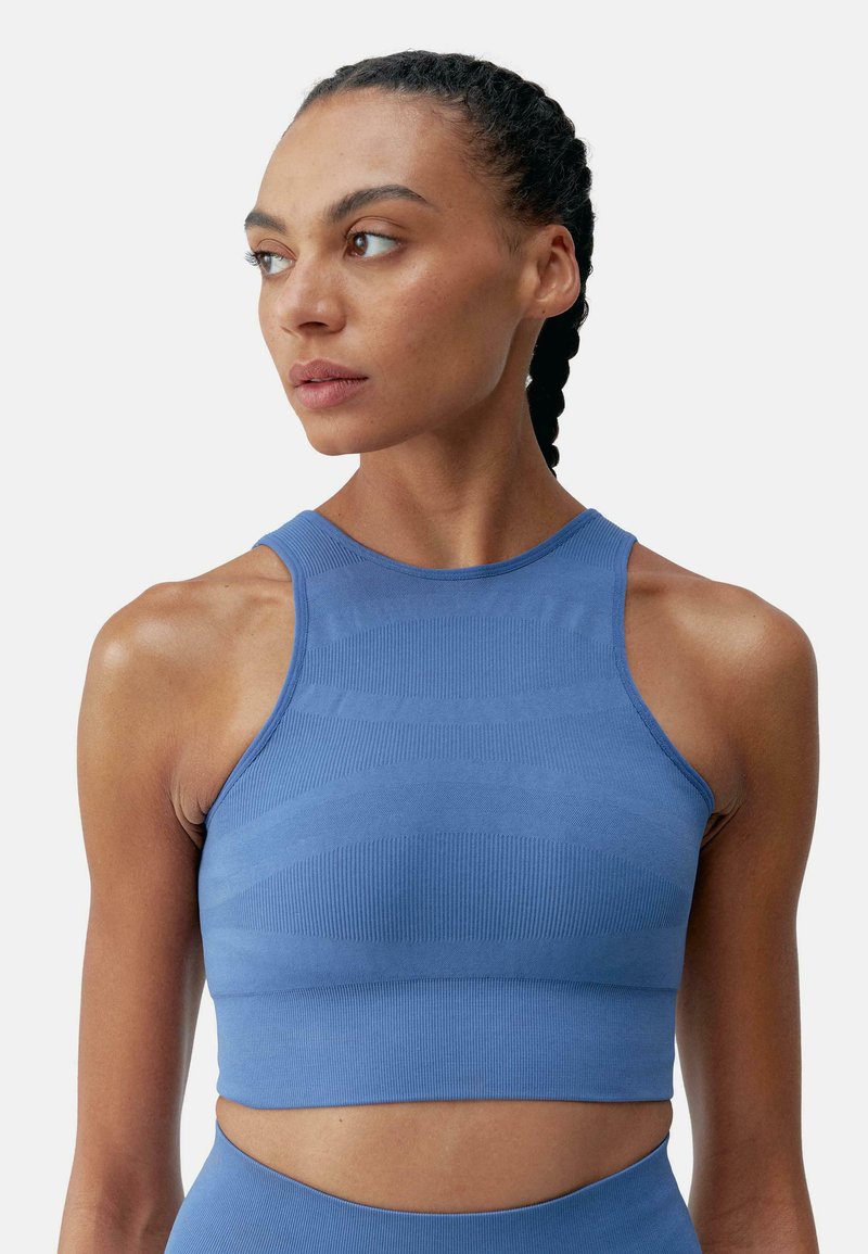 Blå sportig crop top tillverkad av texturerad stickad tyg, med hög halsringning och kontrasterande horisontella ränder.