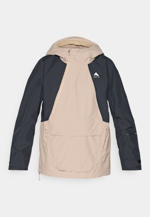 Beige ja tummansininen hupullinen takki, jossa on puolivetoketju, etutasku ja logo rinnassa; valmistettu vedenpitävästä materiaalista, jolla on sileä pinta.