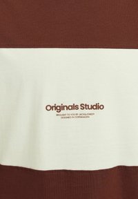 Rudas ir smėlio spalvos dryžuota marškinė, pagaminti iš medvilnės, su lygiu paviršiumi ir spausdintu logotipu "Originals Studio" rudai spalva.