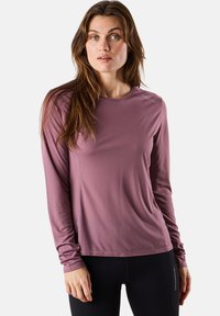 Langsleeve sporttop in gedempt mauve, met een textuurstof, ronde halslijn en subtiele logodetail op de schouder.