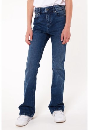 Jeans in denim blu scuro con vita alta, gambe a zampa di elefante, design a cinque tasche e leggero sbiadimento. Indossati con sneakers bianche.