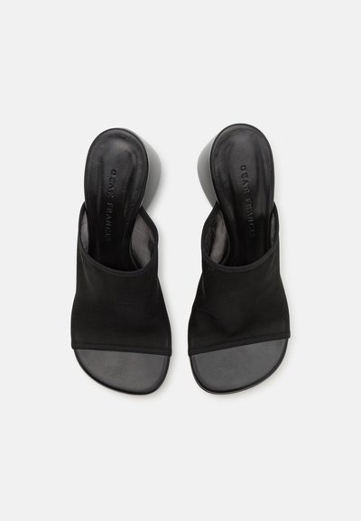 Schwarze Riemchenslipschuhe mit offenem Zehenbereich, gefertigt aus einem weichen Textilobermaterial und mit einer glatten Gummisohle. Das Design ist minimalistisch und hat keine sichtbaren Beschläge.