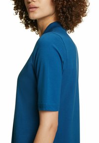 Turquoisekleurig polo-shirt met een ribgebreide kraag en korte mouwen, voorzien van een gestructureerde stof en een licht lose pasvorm.