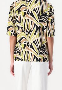 Camicia a maniche corte in tessuto leggero con un vivace motivo di foglie di palma in verde, nero e beige, dal taglio morbido e con scollatura tonda.