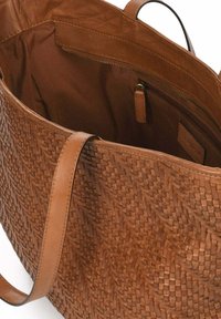 Gran bolso tote de cuero trenzado en marrón con una forma estructurada. El interior cuenta con un bolsillo con cremallera y un forro de tela suave.
