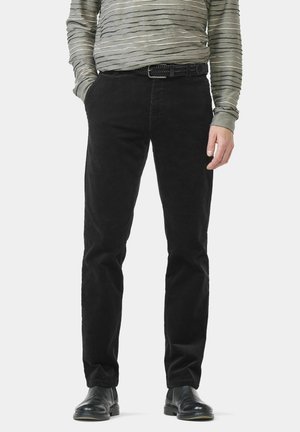 Schwarze Cordhose mit geradem Bein, aus strukturiertem Stoff und mit einfachem schwarzem Gürtel. Kombiniert mit einem grauen, gestreiften Langarmshirt.