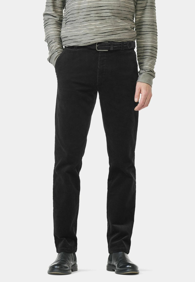 Schwarze Cordhose mit geradem Bein, aus strukturiertem Stoff und mit einfachem schwarzem Gürtel. Kombiniert mit einem grauen, gestreiften Langarmshirt.