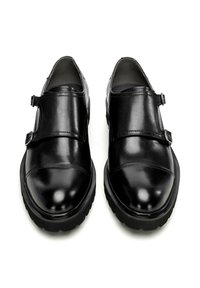 Schwarze Lederschuhe mit doppelten Schnallenriemen, abgerundeter Spitze und einer dicken, strukturierten schwarzen Sohle. Glatte Oberfläche mit minimalen Nähdetails.