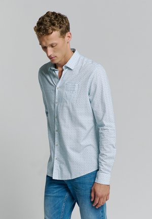 Lichtblauw overhemd met knopen en een geometrisch patroon, lange mouwen, één borstzak, gecombineerd met denim jeans. Soepele textuur.