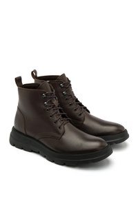 Brązowe skórzane botki za kostkę z okrągłym noskiem, sznurowane z przodu, z miękką podszewką i solidną gumową podeszwą. Posiadają pętle do łatwego zakładania.