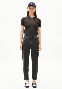 Jeans noirs taille haute à coupe droite, assortis à un t-shirt gris foncé à manches courtes et une casquette marine avec un logo blanc.