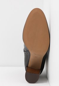 Gray leather shoe with a textured upper, round toe, and brown leather heel. Underside features a smooth tan sole with printed sizing.