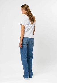 Hvit ribbet topp med korte ermer, kombinert med lyseblå vide jeans med høy midje og klassisk fem-lomme design.