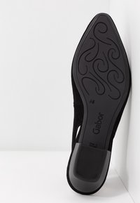Semelle de chaussure noire à bout pointu avec motifs tourbillonnants décoratifs, talon moyen et inscription "Gabor" visible.
