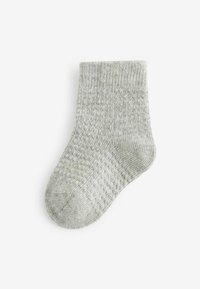 Grå ribbade strumpor med ett texturerat mönster, utrustade med förstärkta tår och mudd. Materialet verkar mjukt och mysigt, lämpligt för avslappnad användning.