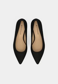 Ballerines noires à bout pointu avec une texture lisse semblable au daim, présentant un design échancré et une semelle intérieure beige, estampillée "Peter Kaiser".