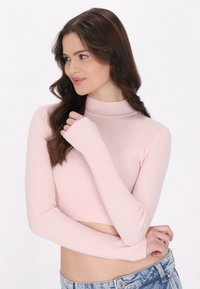 Rippentop in zartem Rosa mit hohem Kragen und langen Ärmeln. Der Stoff hat eine glatte Textur und weist ein tailliertes Design auf.
