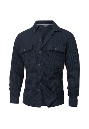 Marineblauwe shirtjack gemaakt van gestructureerde stof met een visgraat patroon, voorzien van twee borstzakken, knoopsluiting en lange mouwen.