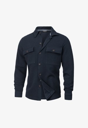 Chaqueta de camisa azul marina hecha de tejido texturizado con patrón de espiga, que cuenta con dos bolsillos en el pecho, cierre de botones y mangas largas.