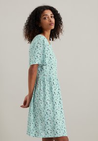 Lichtblauw jurkje met een comfortabele pasvorm, korte mouwen en bloemenpatronen. De zoom is licht uitlopend en de stof heeft een zachte textuur.