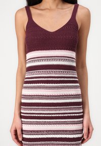 Vestido de malha com um decote em V profundo e alças finas, com uma parte superior bordô e riscas horizontais alternadas em branco e rosa.