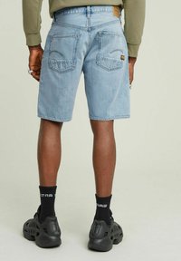 Shorts in denim bluastro con una vestibilità comoda, cinque tasche e una patch con marchio sul retro. Abbinati a calze e scarpe nere.