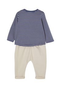 Gestreiftes Langarmoberteil in Marineblau und Creme, kombiniert mit Cremefarbenen Hosen. Es hat einen lockeren Schnitt und umgeschlagene Bündchen. Hergestellt aus weichem Stoff.