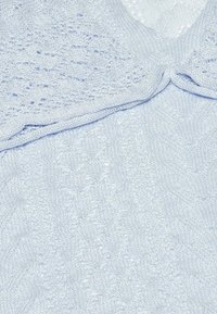 Hellblaues Strickpullover mit verschiedenen strukturierten Mustern, gerippten Abschlüssen und einem V-Ausschnitt-Design. Der Stoff wirkt weich und leicht.