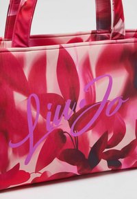 Borsa a spalla con stampa floreale rosa e logo "Liu Jo" viola, materiale in tessuto, doppi manici e una texture liscia. Presenta diverse tonalità di rosa.