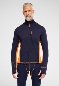 Marineblå og orange zip-jakke med høj krave, lavet af et struktureret materiale, der har en frontlomme og kontrastsyninger.