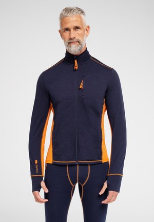 Marineblå og orange zip-jakke med høj krave, lavet af et struktureret materiale, der har en frontlomme og kontrastsyninger.