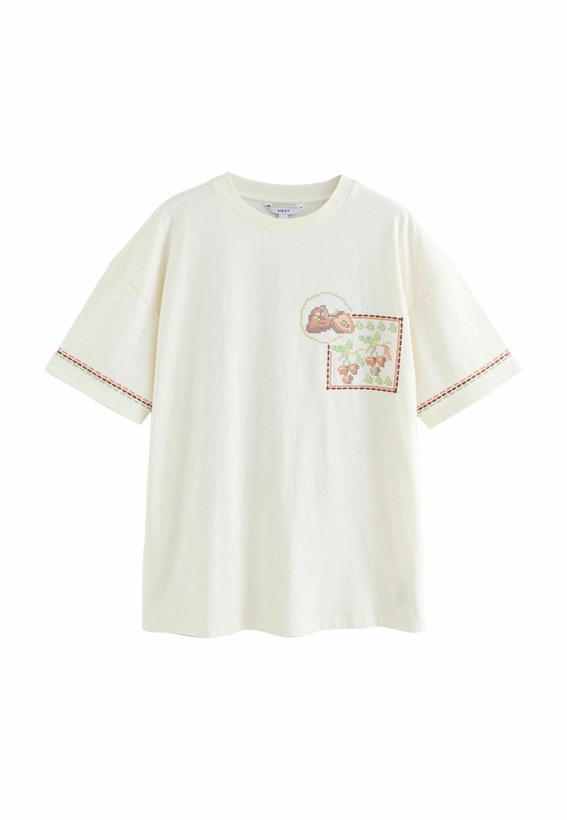 Krémové bavlnené tričko s krátkymi rukávmi, s náprsníkovou kapsou s kvetinovou výšivkou a kontrastnými stehovými detailmi na rukávoch.